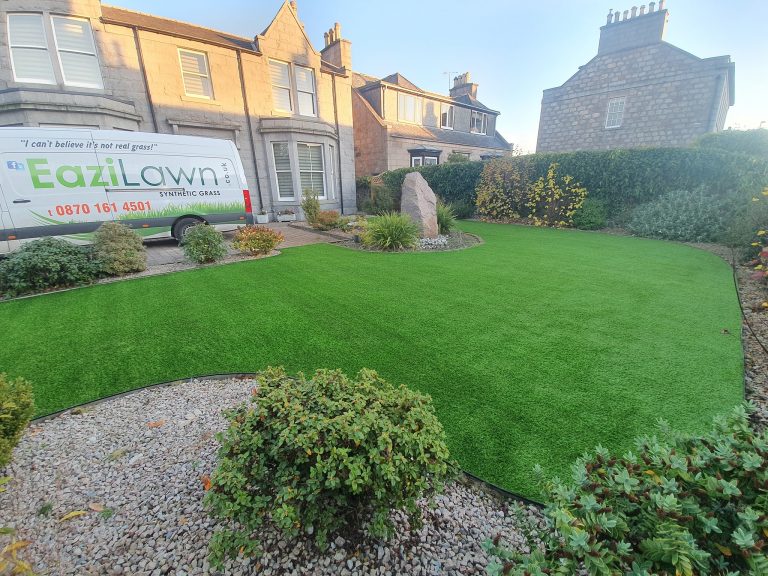 A large lawn with hedges and a border around it. An EaziLawn van parked outside the house.